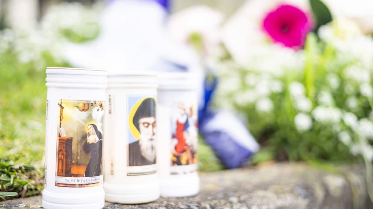 Three candles laid out next to a bouquet of flowers.