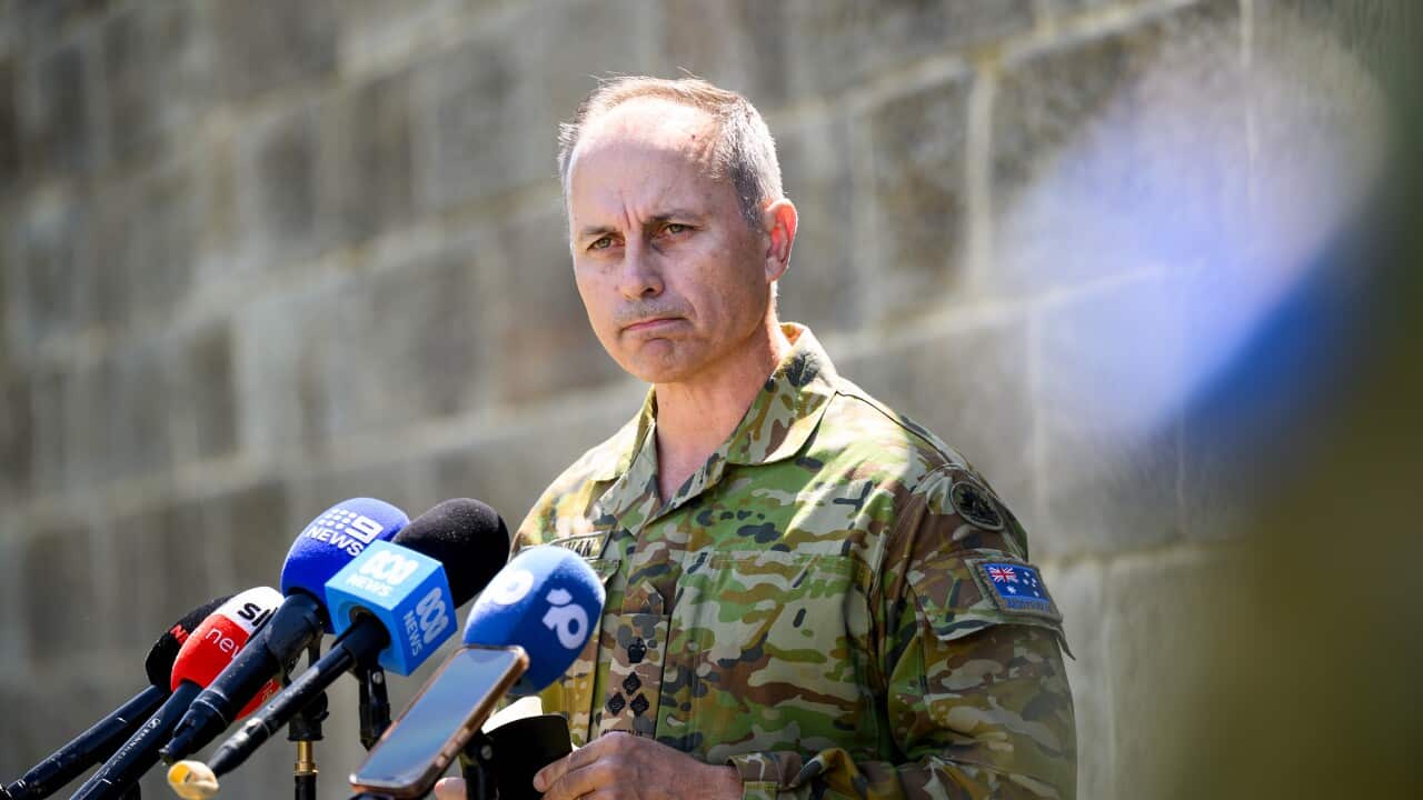 A man in military uniform with a glum look on his face speaks to the media.