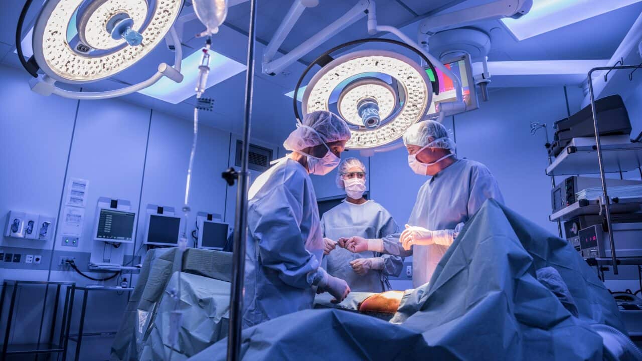 Surgeons operating on patient in operating theatre under lights