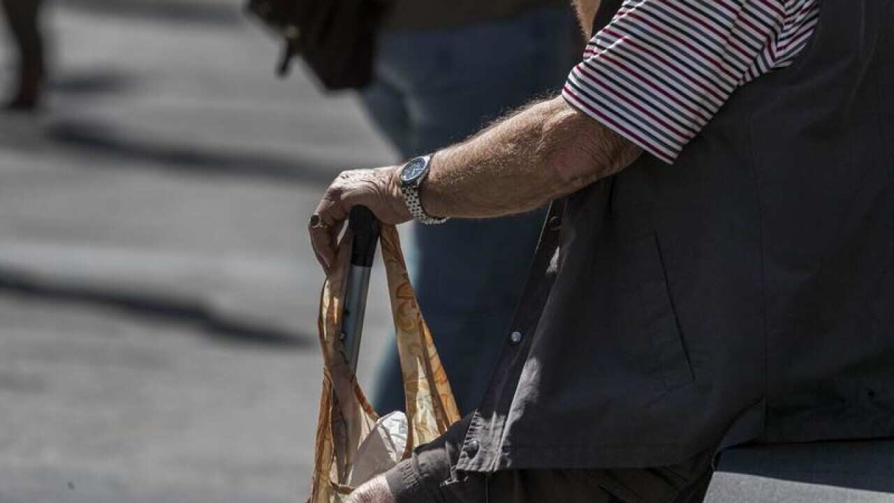 An elderly man sits on a bench, in Brisbane.