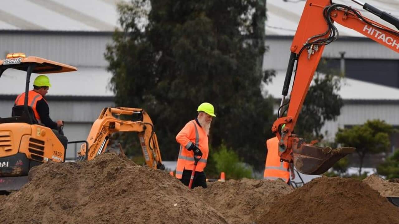 Workmen are seen digging a series of graves.