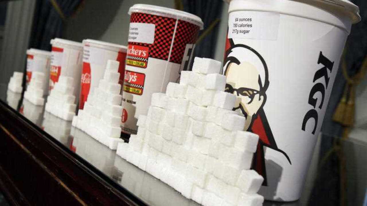 A display of various size soft drink cups next to stacks of sugar cubes