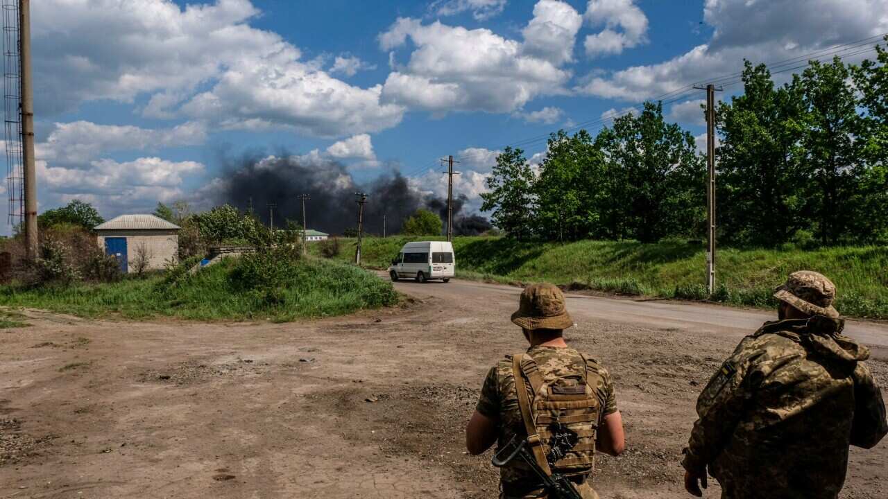 Troops look at smoke from an oil refinery at Lysychans'k