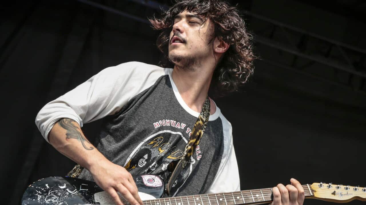 A man playing guitar and singing on stage.