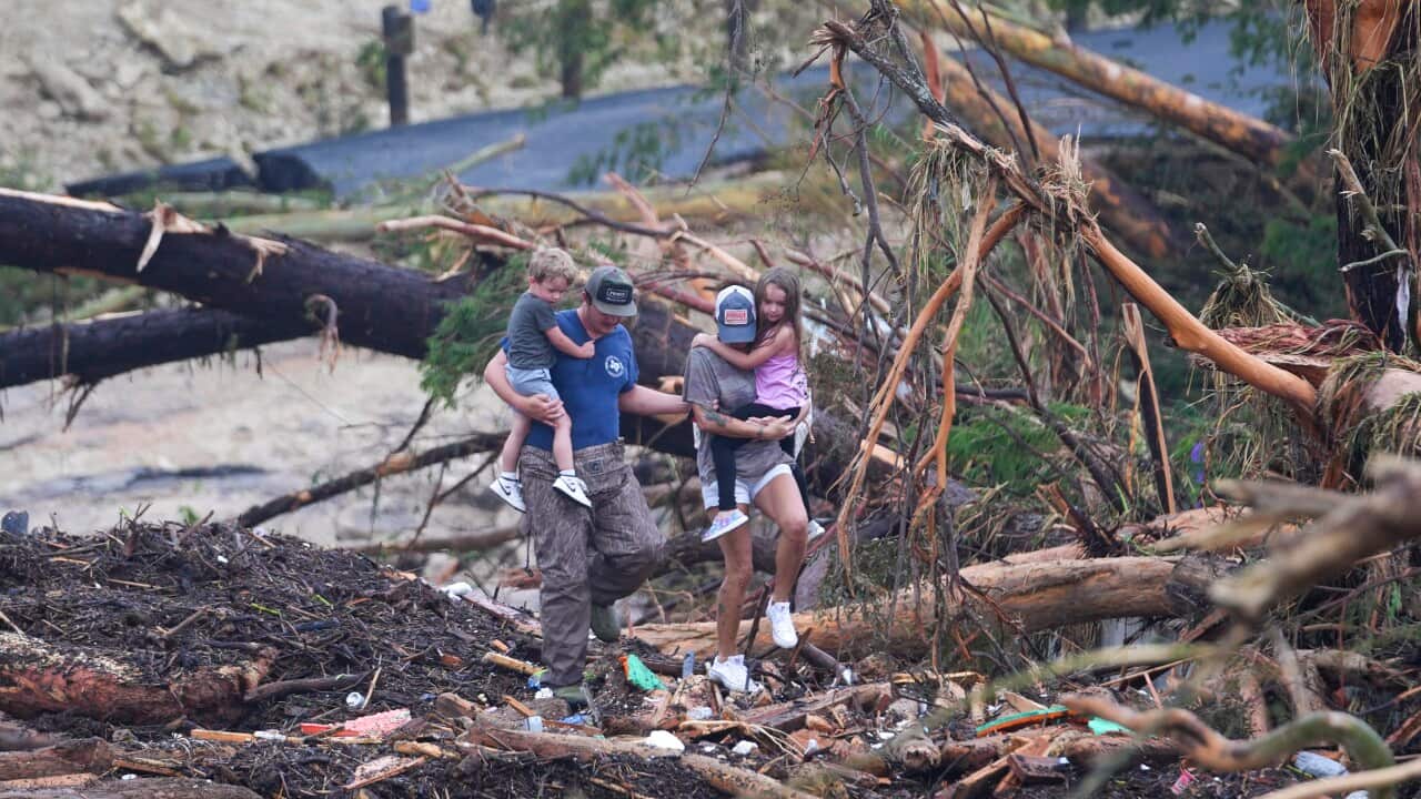 People climb over debris on a bridge atop the Guadalupe River after a flash flood