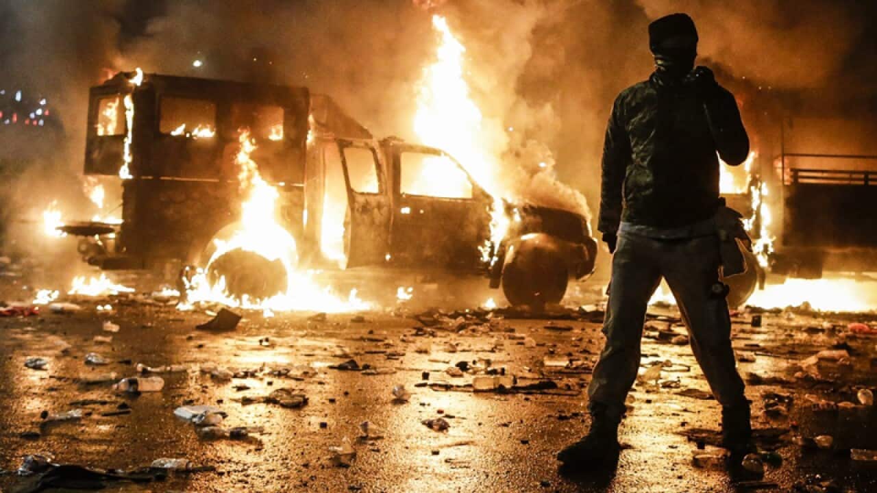 Burning police cars outside the presidential palace in Jakarta