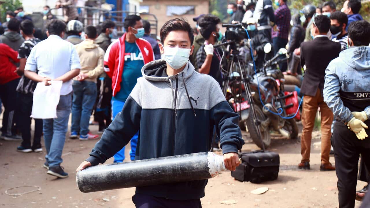A Nepali man carries a cylinder for oxygen in Kathmandu