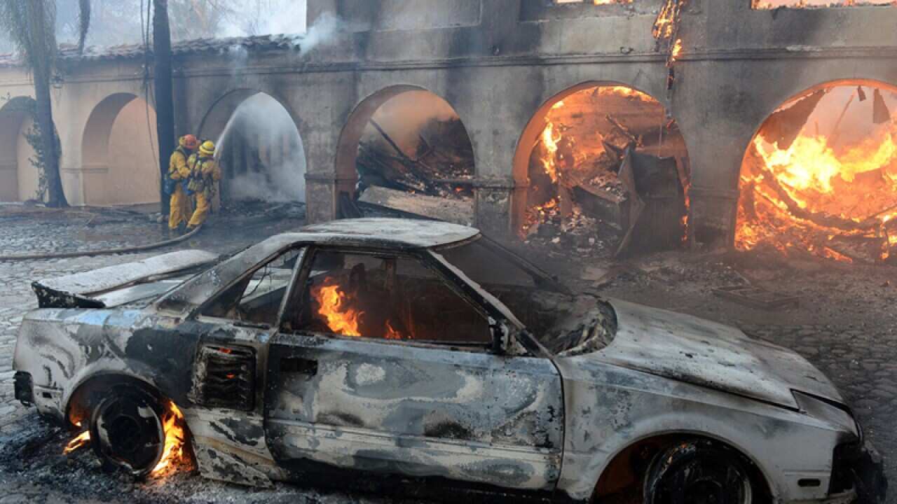 A house and car burn in a wildfire near Los Angeles