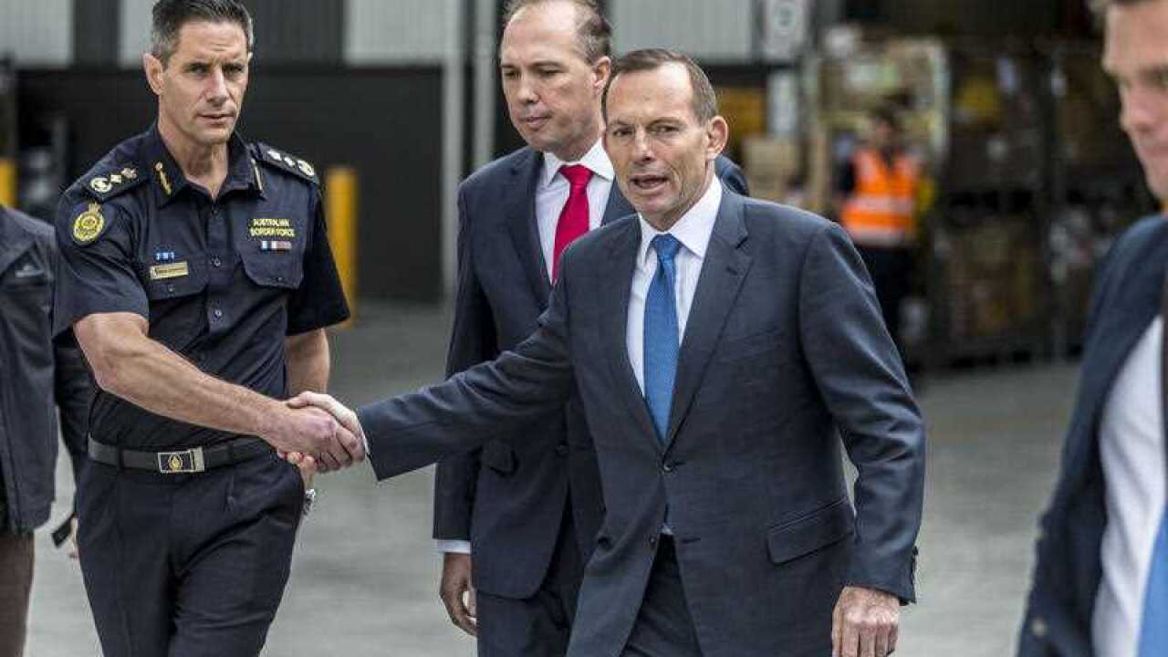 Australian Prime Minister Tony Abbott shakes hands with Roman Quaedvlieg, a member of the Australian Border Force