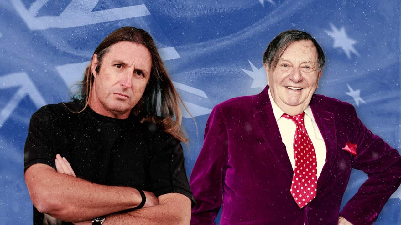 A man in a black shirt standing next to a man in a pink velvet suit.