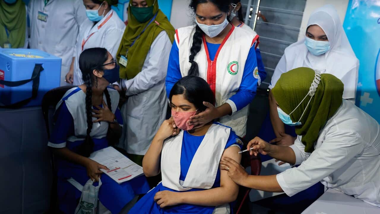 A health worker administers a dose of Pfizer-BioNTech COVID-19 Vaccine to a student at Ideal School and College in Dhaka, Bangladesh.