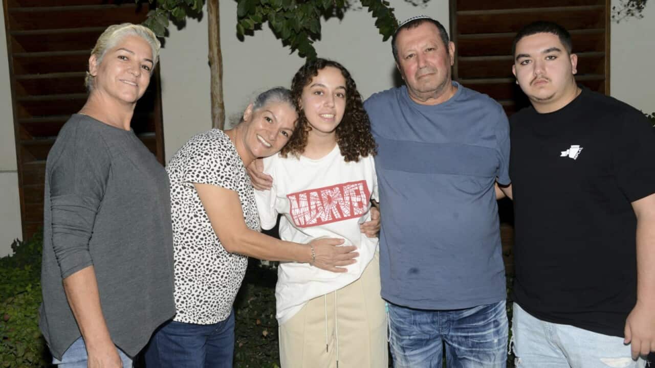 Israeli soldier Ori Megidish, wearing a white Marvel T-shirt, stands in the middle of four relatives, with their arms around each other.