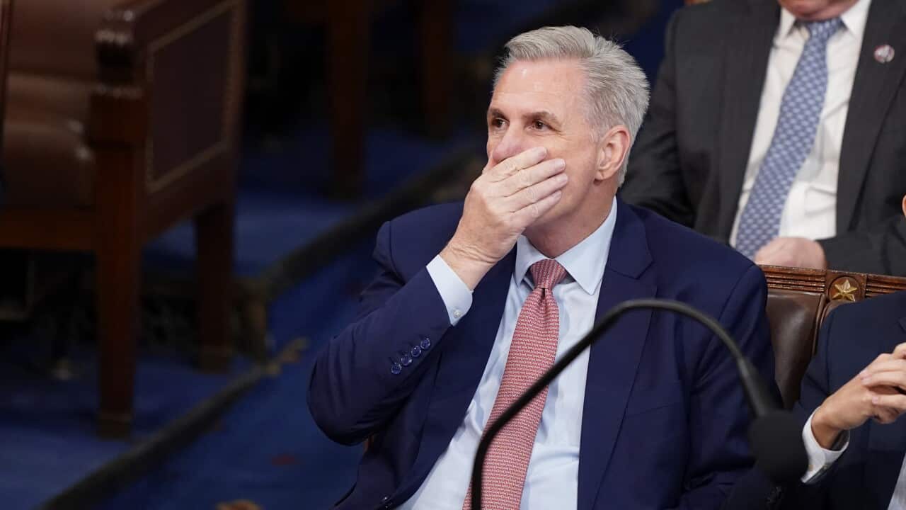 A man in a suit covering his mouth