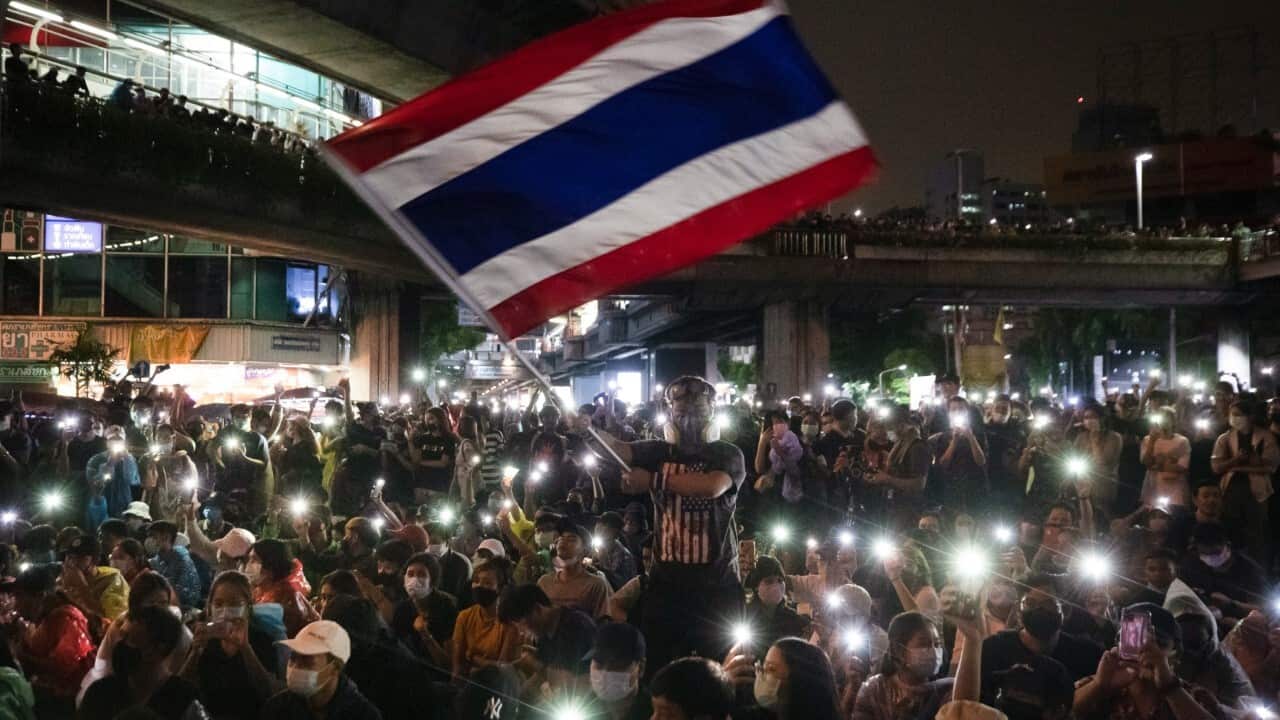Pro-democracy protesters waves Thailand national flag as others shine their mobile phone lights during an anti-government protest in Bangkok, Thailand, Sunday, Oct. 18, 2020 (AAP Image-AP Photo-Sakchai Lalit)