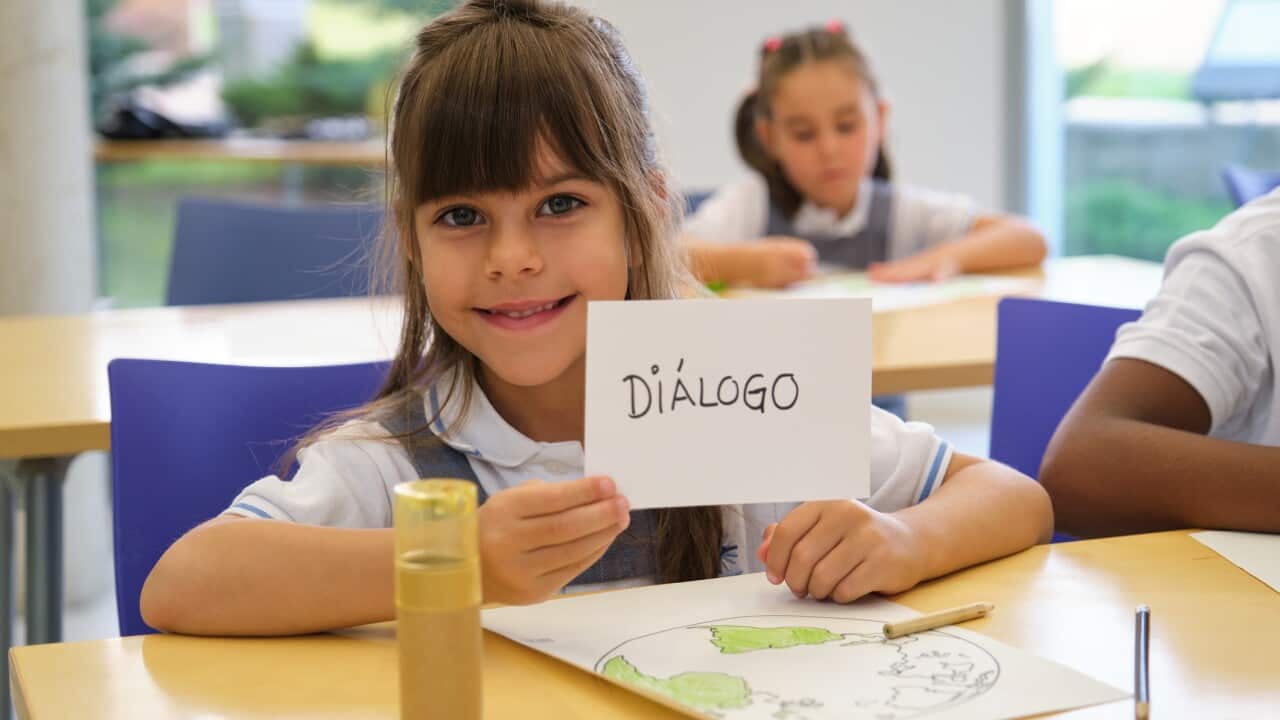 Smiling student showing dialogue sign in classroom