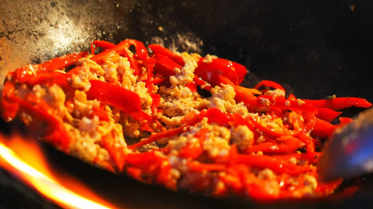 A Chinese chef cooks fried eggs with chilli peppers