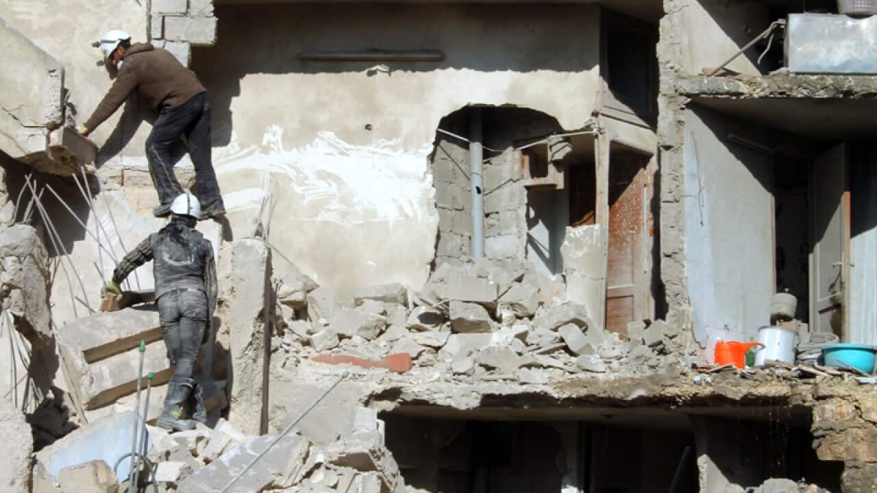 Rescuers climb on the rubble of a destroyed building in Aleppo