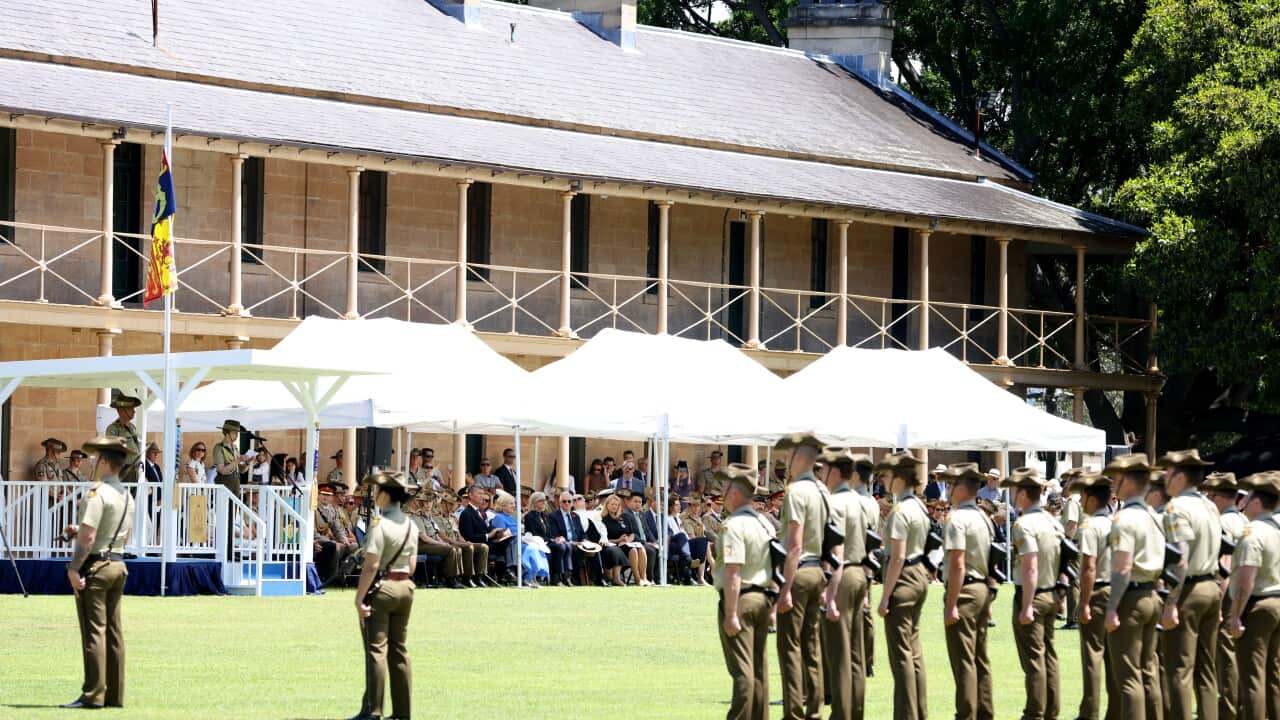 Military personnel in uniform stand in formation for an event at a milutary barracks