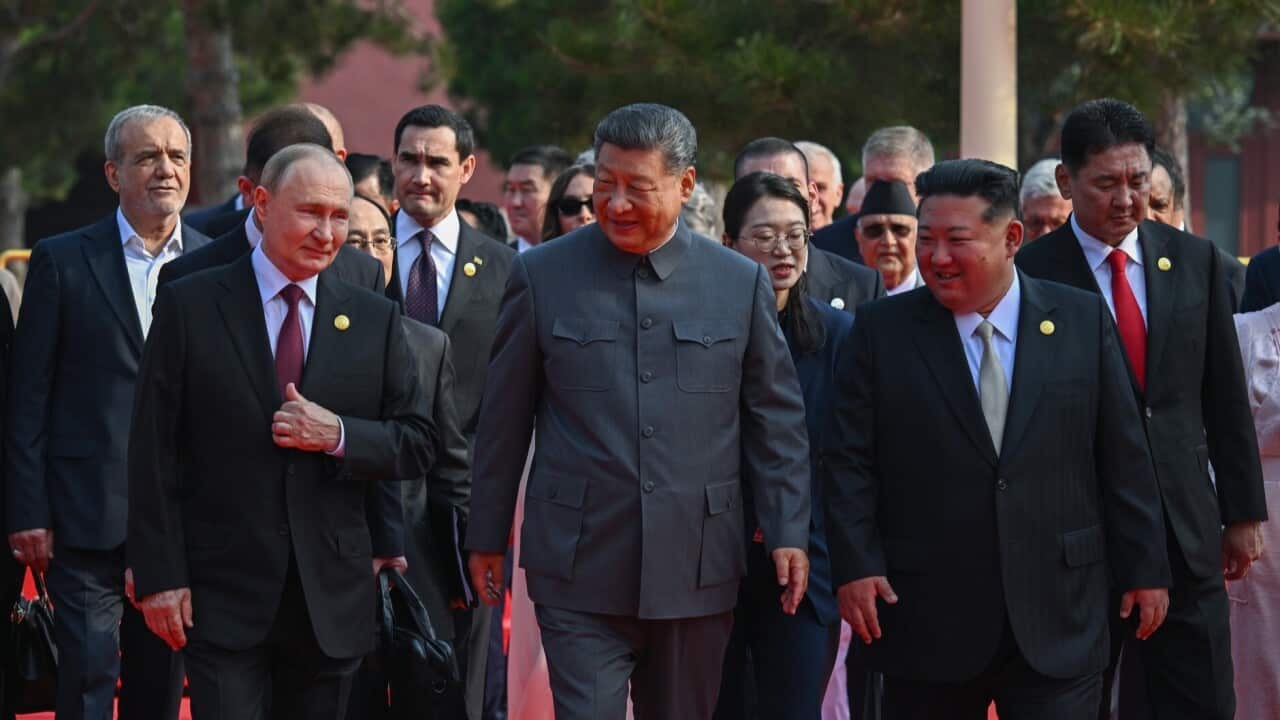 Three male leaders walk alongside on another, with others behind them.