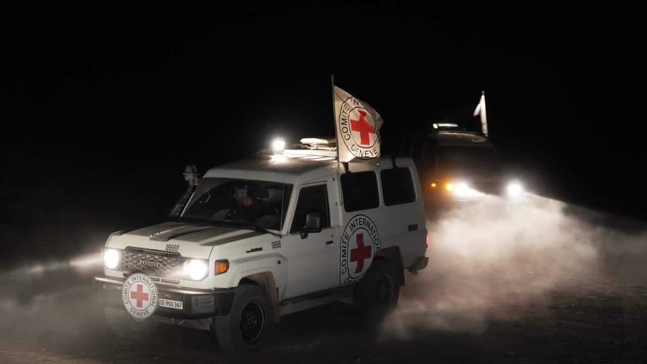 A white four-wheel drive with a red cross on its side and a flag driving in the night