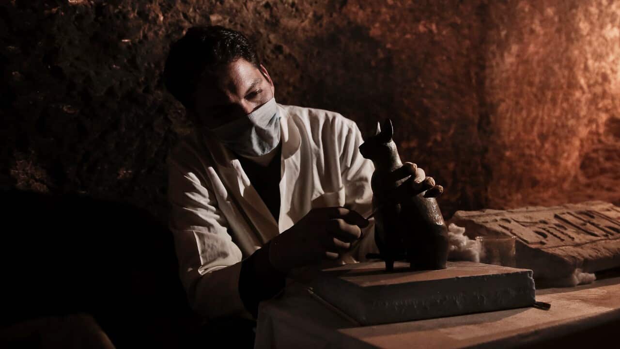An archaeologists works on a statue inside a tomb, at an ancient necropolis near Egypt's famed pyramids in Saqqara, Giza, Egypt.