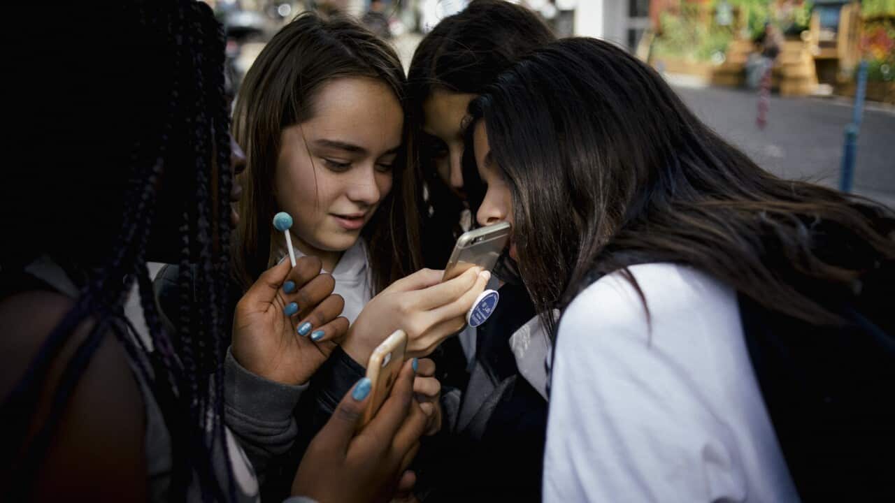 Teenagers use their phones after school in Paris