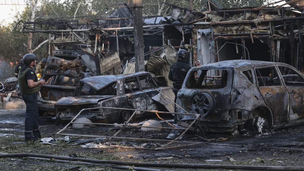 Ukrainian police officers inspect the damage and burnt out cars