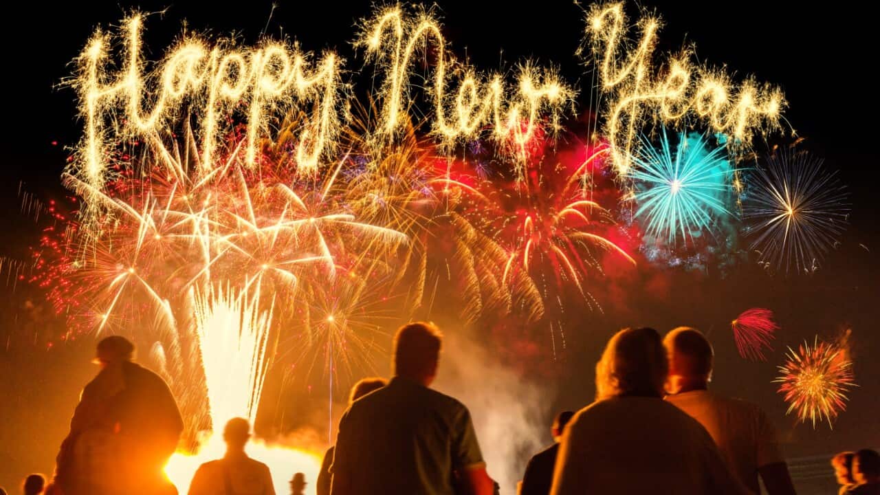 People standing in front of colorful fireworks.