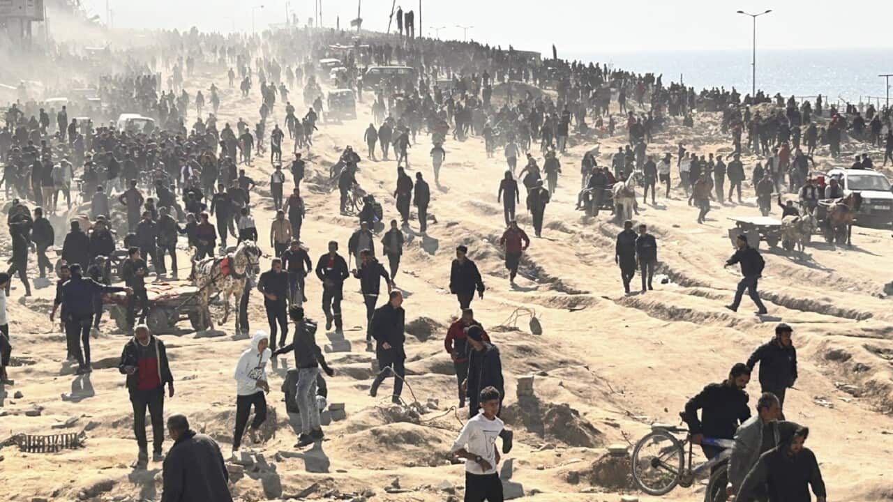 Palestinians wait for humanitarian aid on a beachfront in Gaza City.
