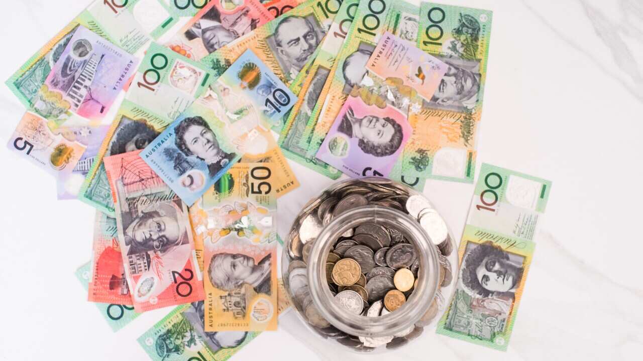 Top view of a jar with coins and Australian dollar banknotes on the white background