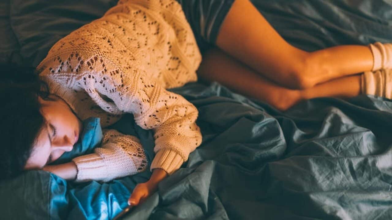 Sad woman in bed text messaging
