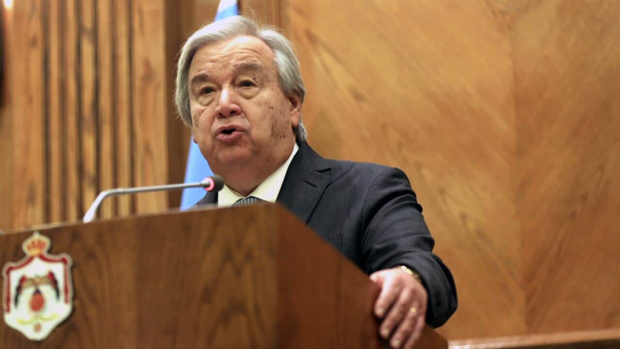 A man in a dark suit with grey hair stands behind a podium