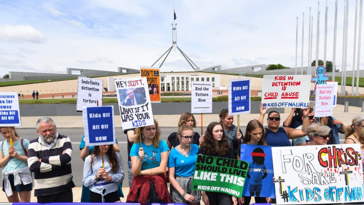 Protesters hold up signs during a rally demanding the resettlement of kids held on Nauru