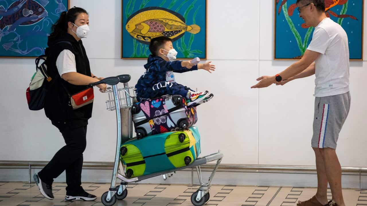 People wearing protective face masks to protect themselves from coronavirus are seen at Brisbane International Airport.