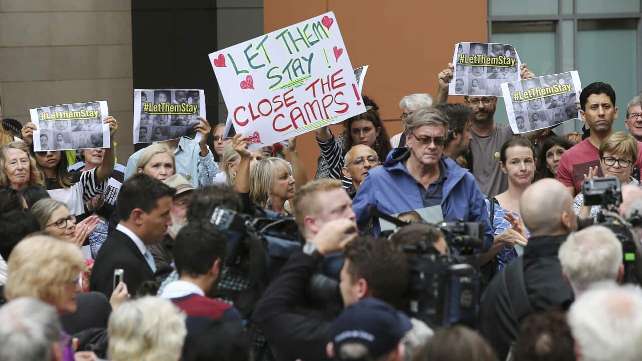 Protestors hold signs up during a rally to protest against asylum seekers being deported in Sydney 