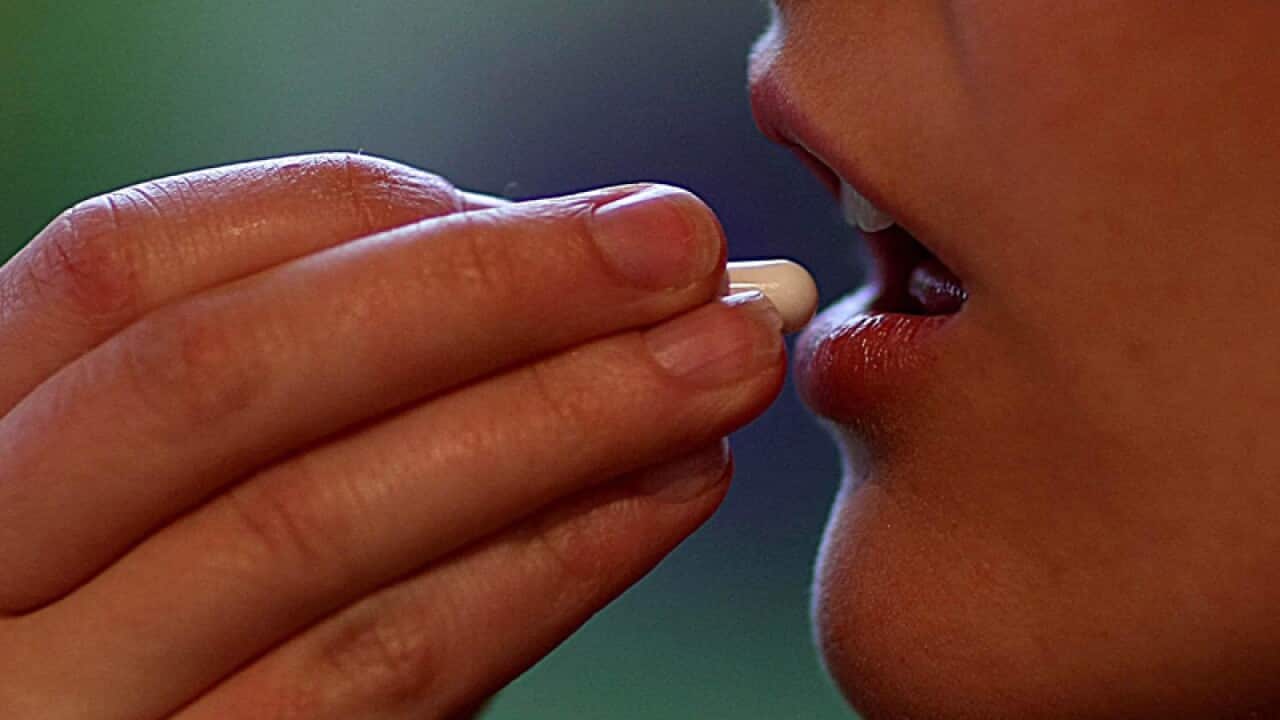 A woman takes a tablet.