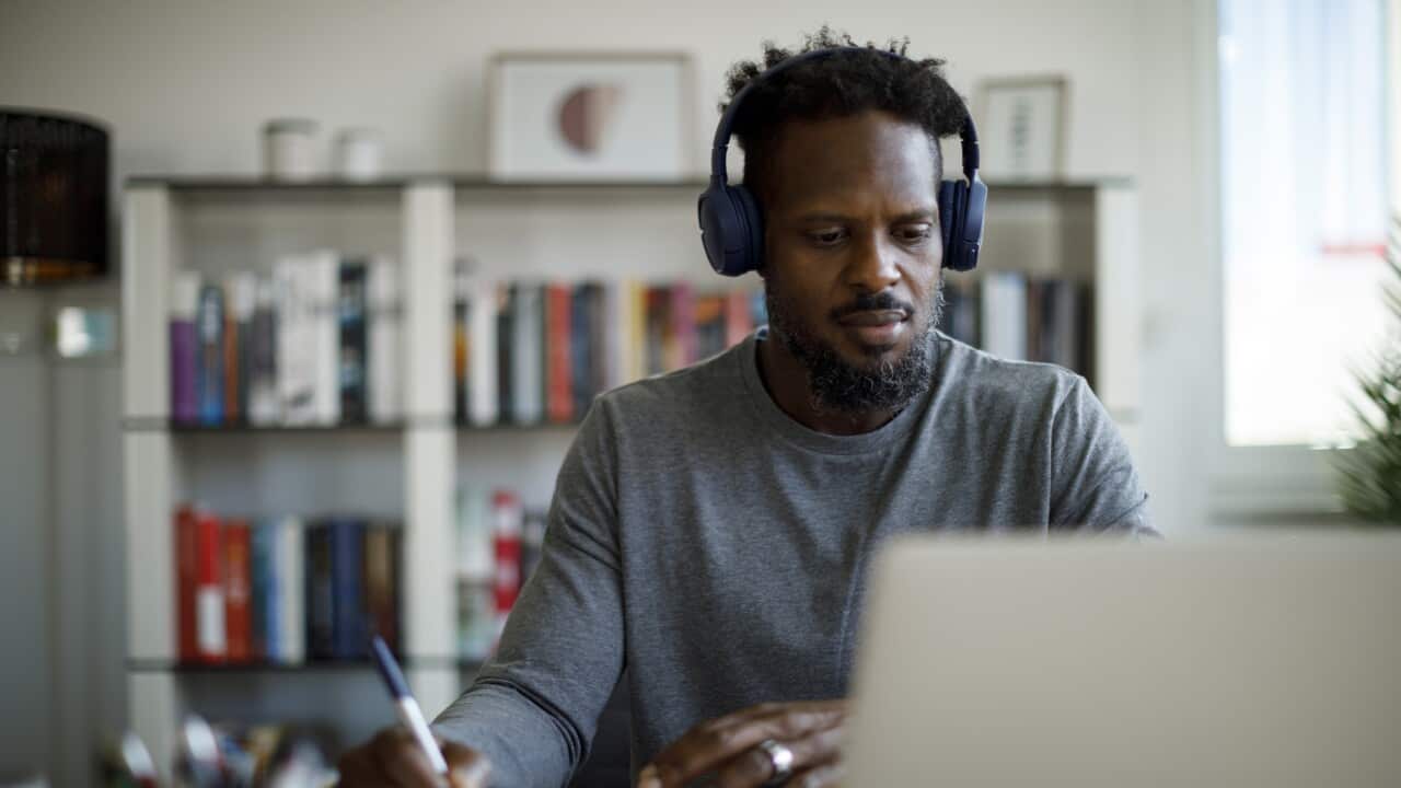 Man with bluetooth headphones attends an online course at home