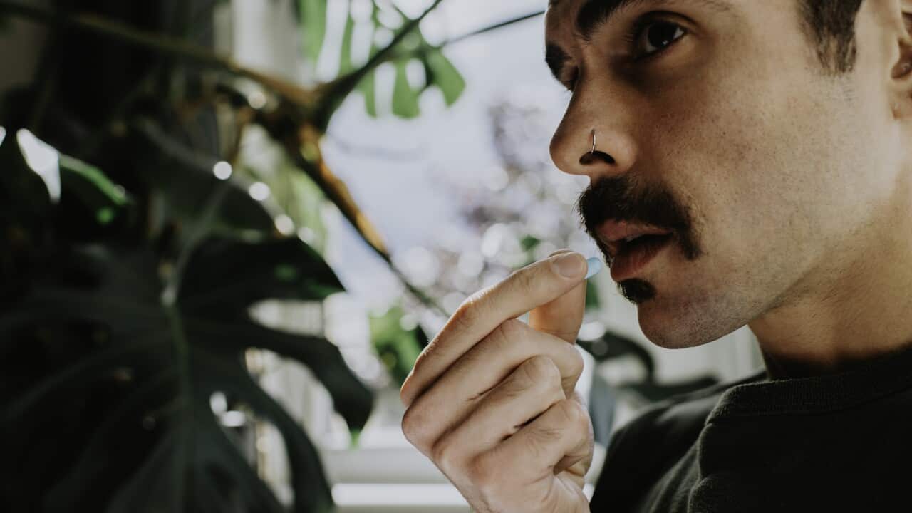 Close-up of a man taking a blue pill