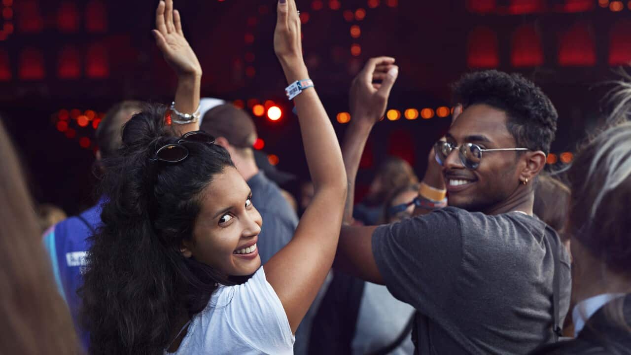 Woman smiling to camera at concert in a crowd of people.