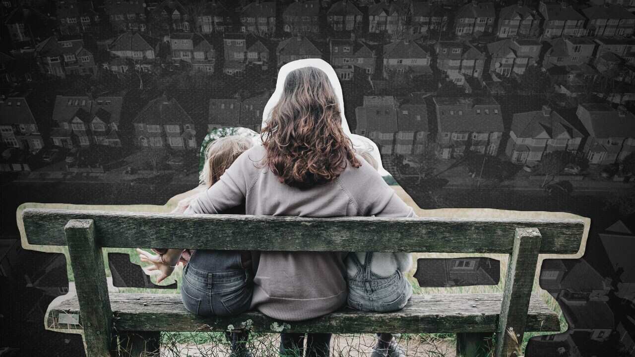 A woman sits with two children on a park bench.