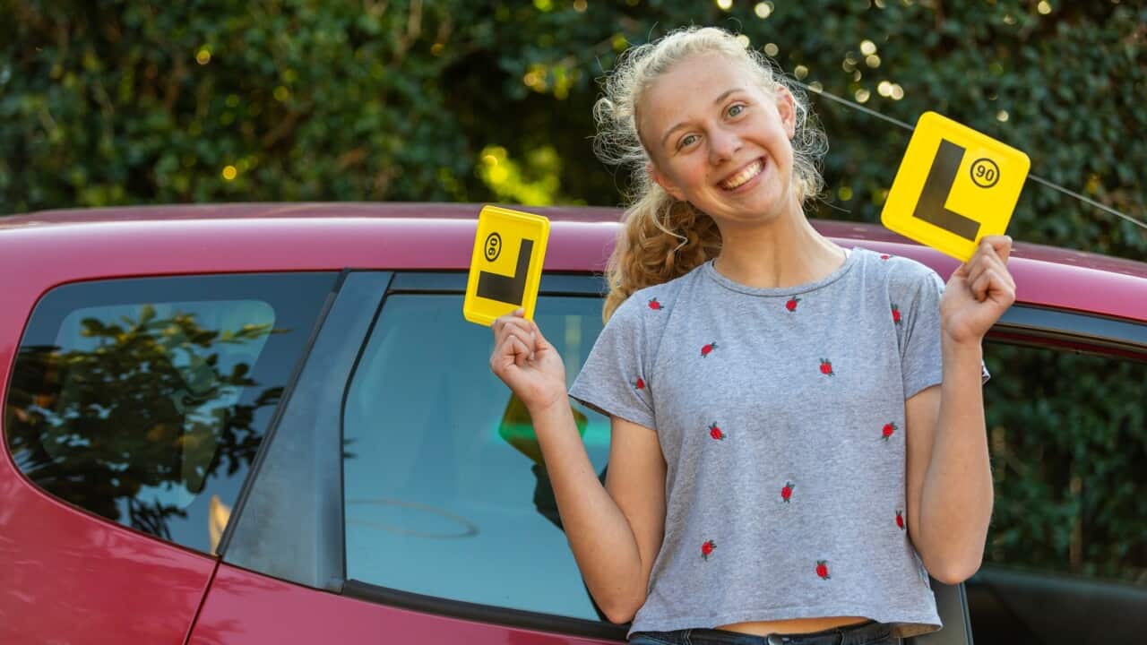 Girl standing in fron of car with L plates