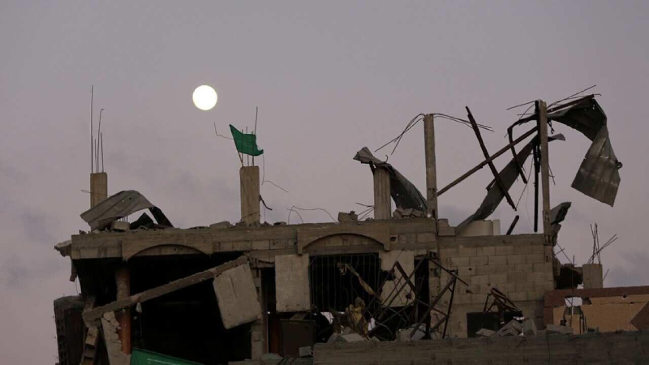 Hamas flags fly at the top of a destroyed house in Gaza city