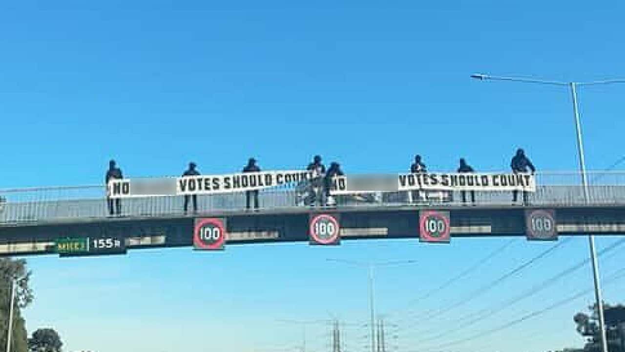 A group of people holding two banners with offensive slogans.