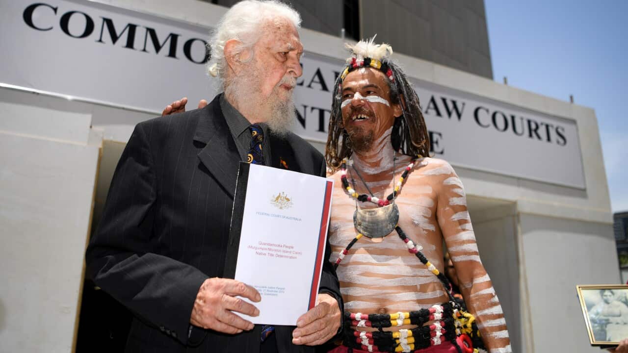 Morton Island Native Title applicant and Quandamooka Ngugi Elder Uncle Bob Anderson (left) is congratulated by traditional dancer Joshua Walker.