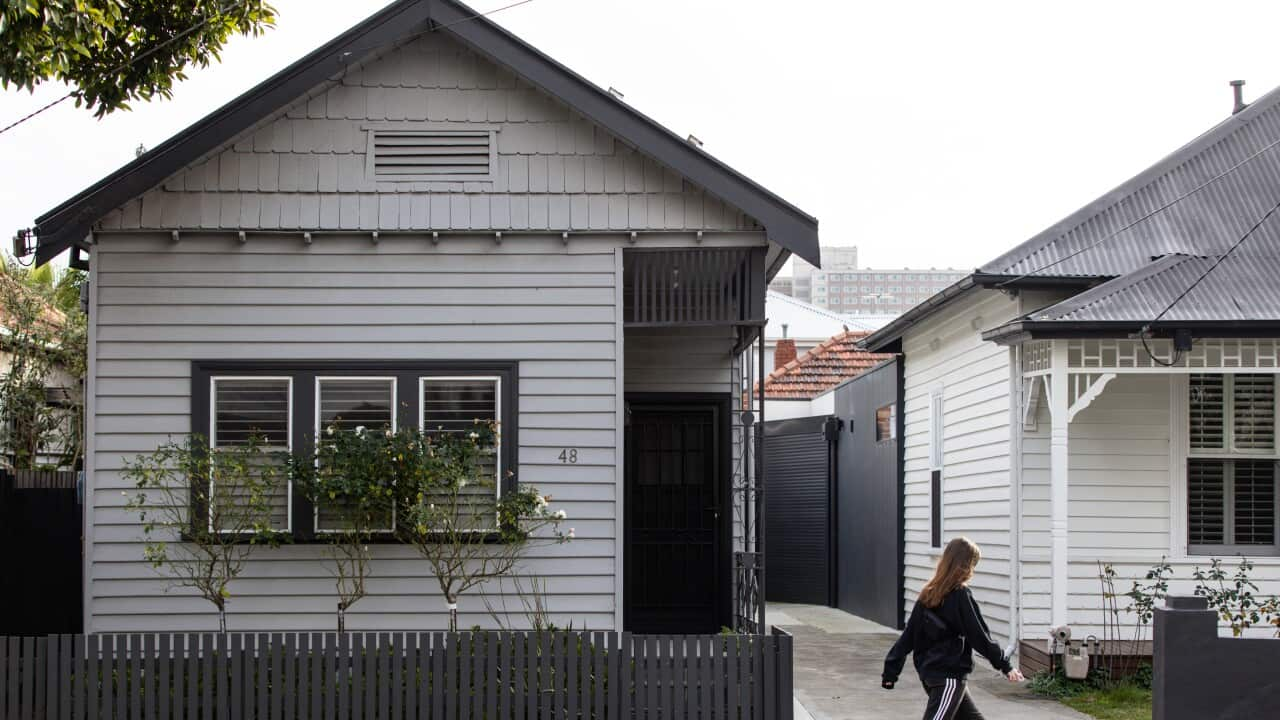 A woman walks past a residential property in Melbourne.