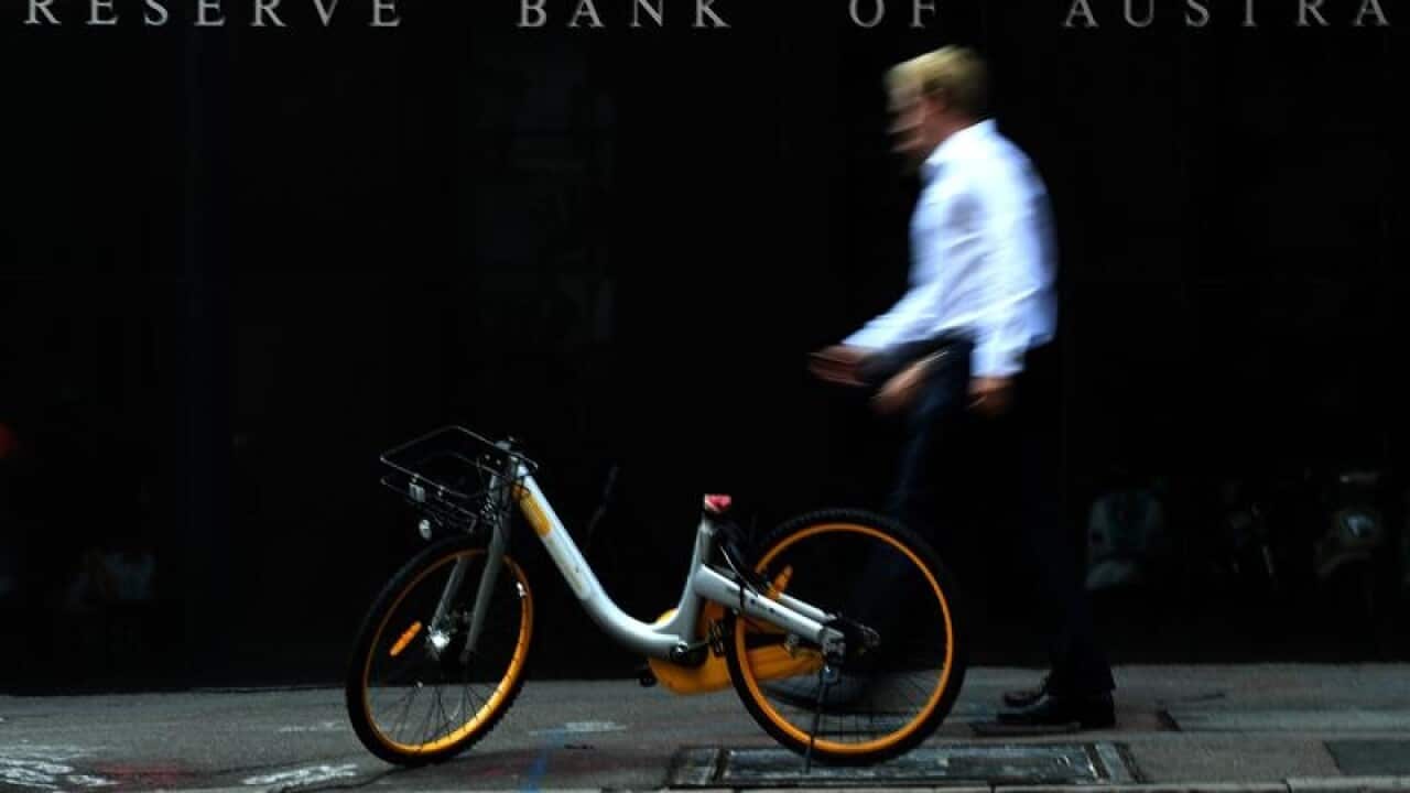 A man walks past a share bike that is in front of the RBA building.