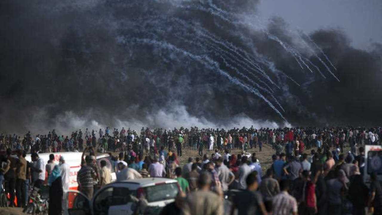 Teargas canisters fired by Israeli troops fall over Palestinians during Friday's protest.
