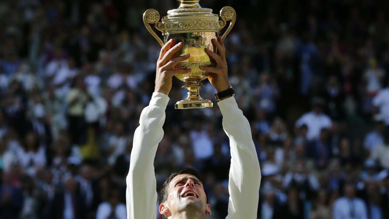 Novak Djokovic holds up the trophy after defeating Roger Federer