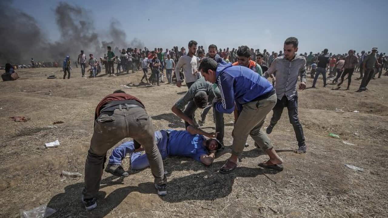 Palestinians protesters try to help a wounded protester during clashes after protests near the border with Israel in the east of Gaza Strip, 14 May 2018