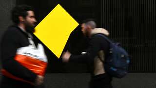 People walking past a building with the Commonwealth Bank logo.